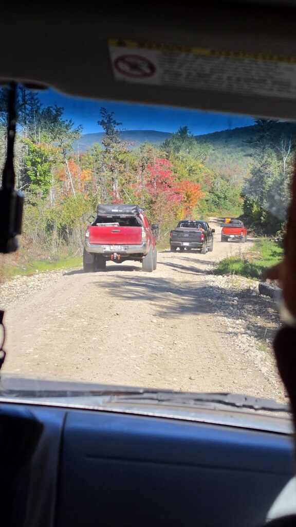 Guide trucks staged along a wooded Rangeley road